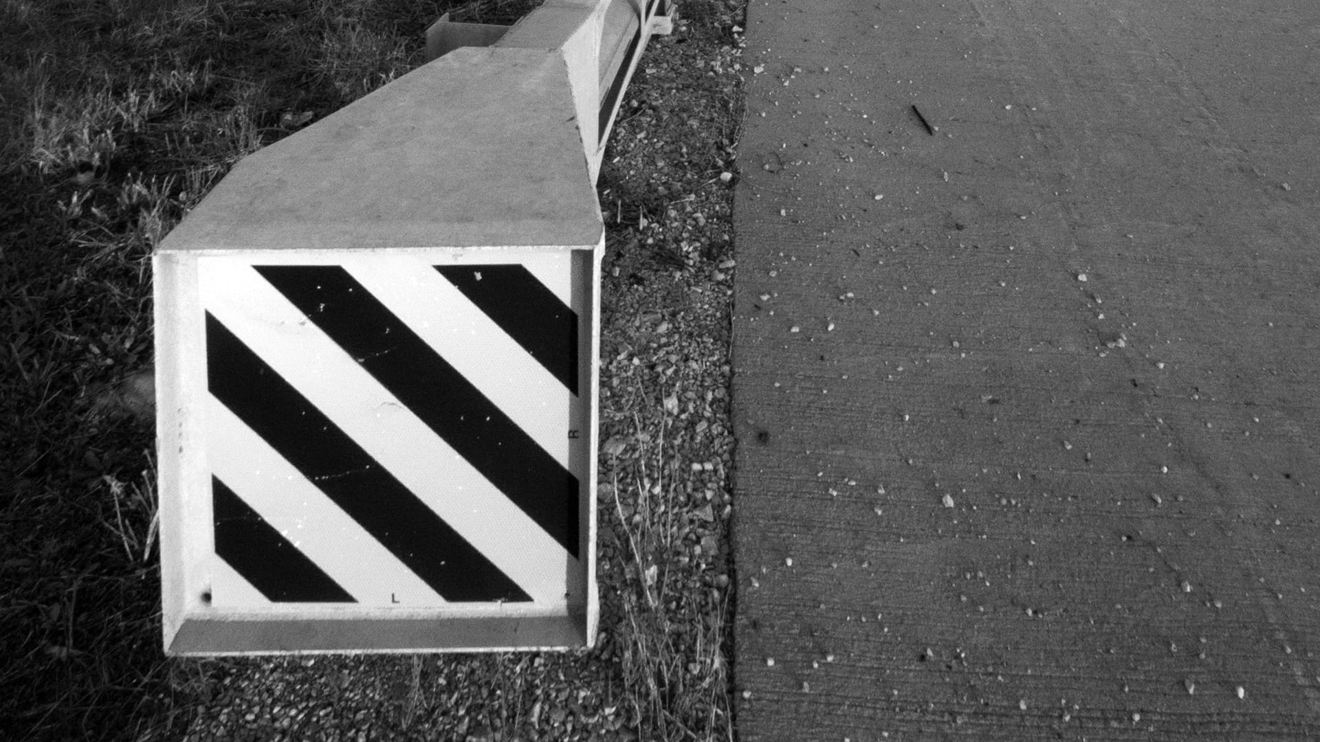 Concrete barrier end terminal with black and white diagonal hazard markings — Tennessee Guardrail energy-absorbing end terminal installation